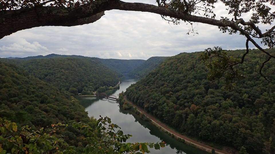 A river winding through a forested valley with a bridge and a road.