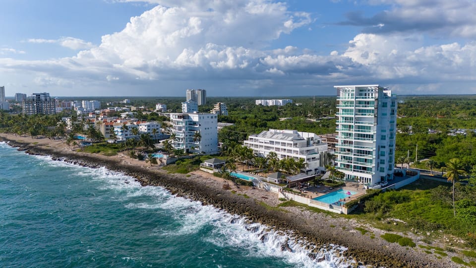 A coastal cityscape with a beach, ocean waves, and modern buildings.