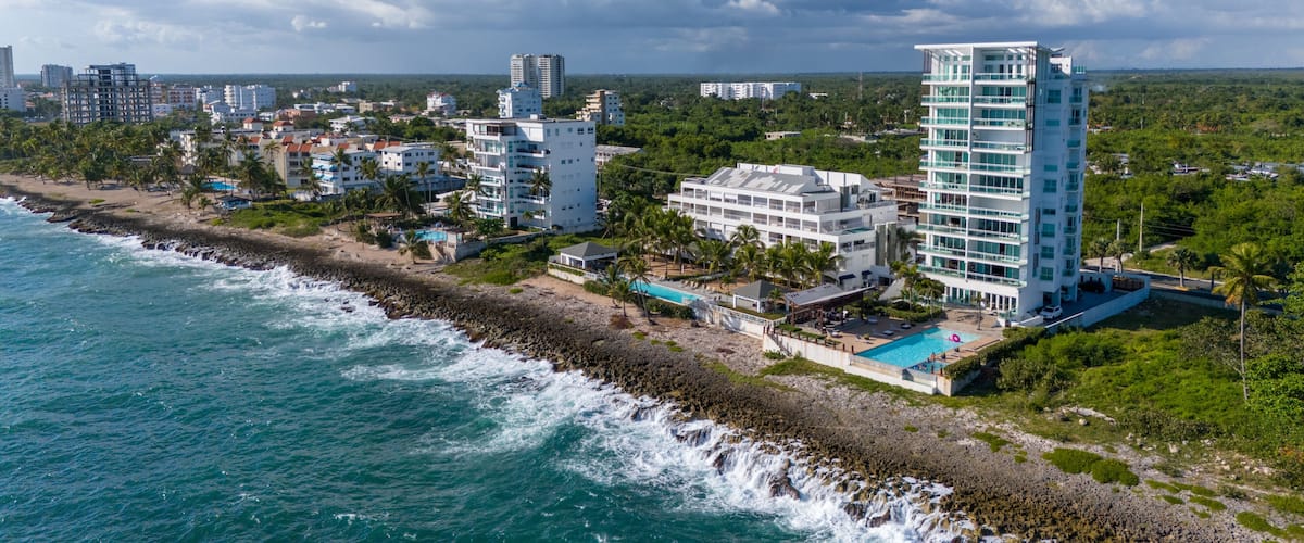 A coastal cityscape with a beach, ocean waves, and modern buildings.