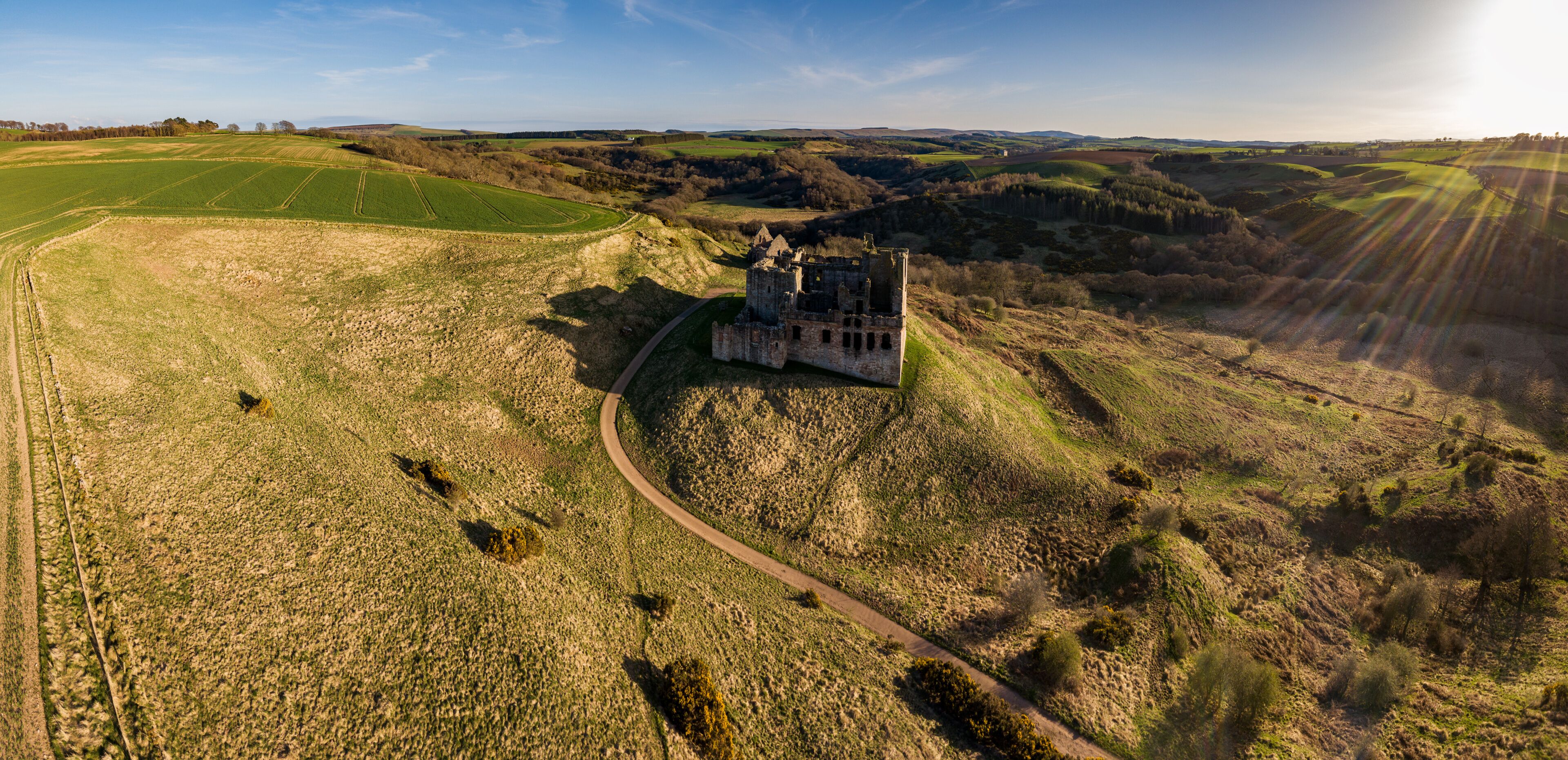 A castle on a hill surrounded by fields and a clear sky.