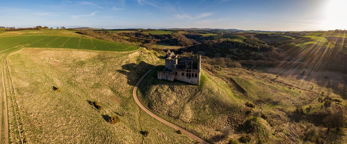 A castle on a hill surrounded by fields and a clear sky.
