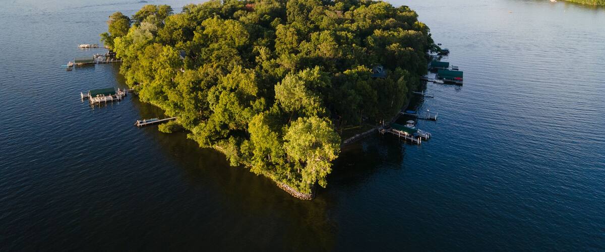 An island surrounded by water with docks and boats.