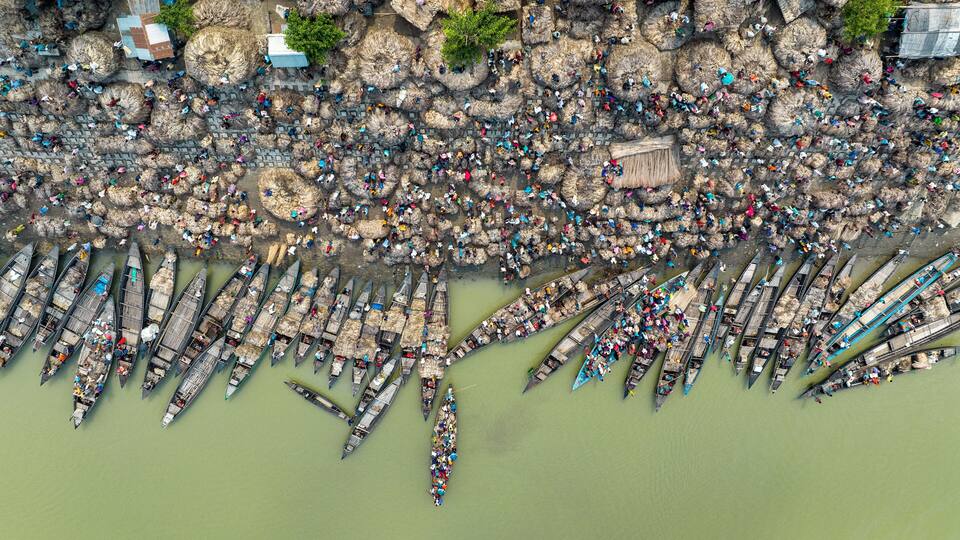 A densely packed group of traditional boats docked along a riverbank.