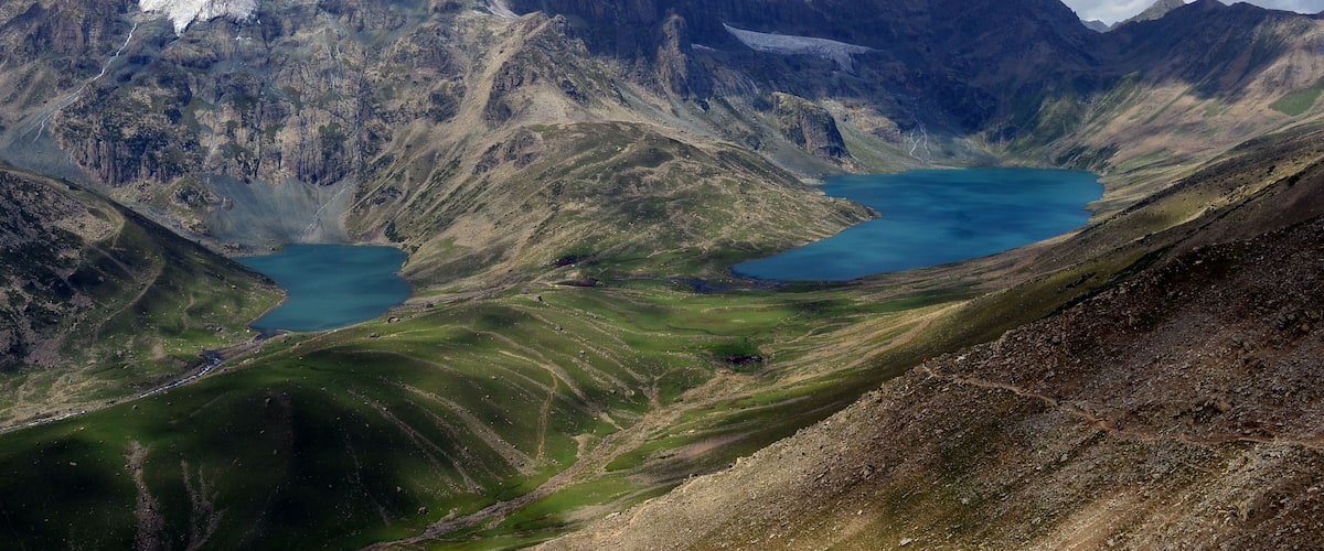 A mountainous landscape with a lake surrounded by rugged terrain and snow-capped peaks.