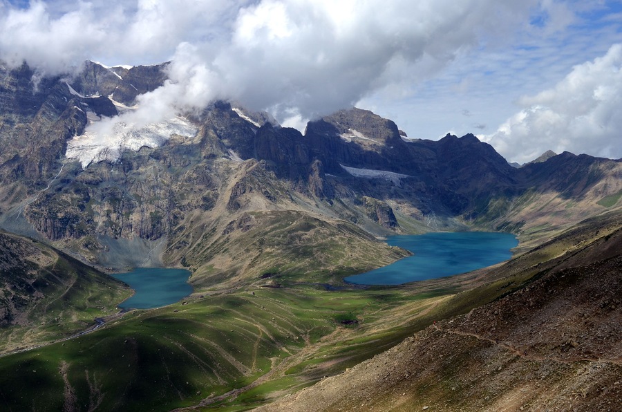 A mountainous landscape with a lake surrounded by rugged terrain and snow-capped peaks.