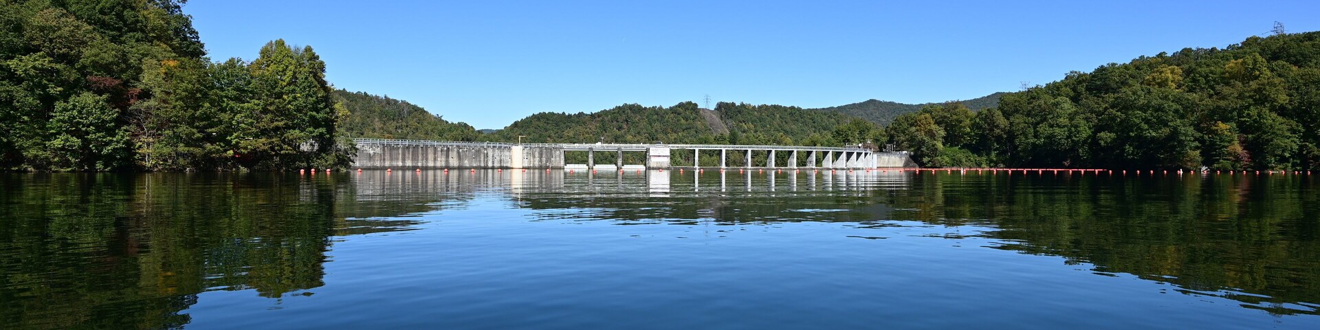 Santeetlah Dam on Lake Santeetlah and Cheoah River in Graham County, North Carolina reflected in calm water of lake on clear autumn afternoon.