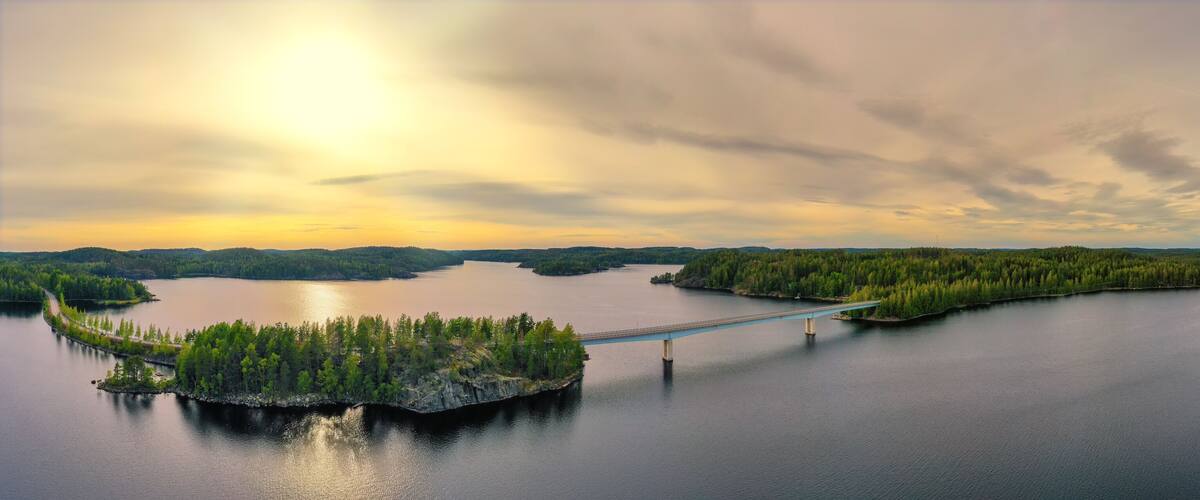 A bridge over a calm lake surrounded by forested islands.