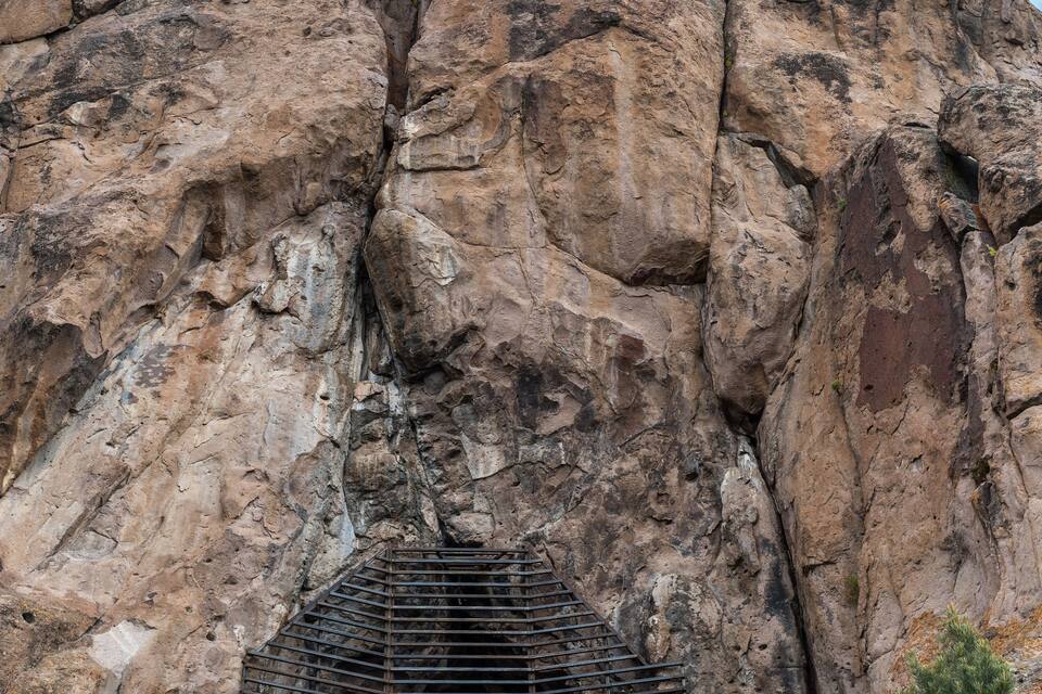 A rocky cliff with a metal structure at its base.