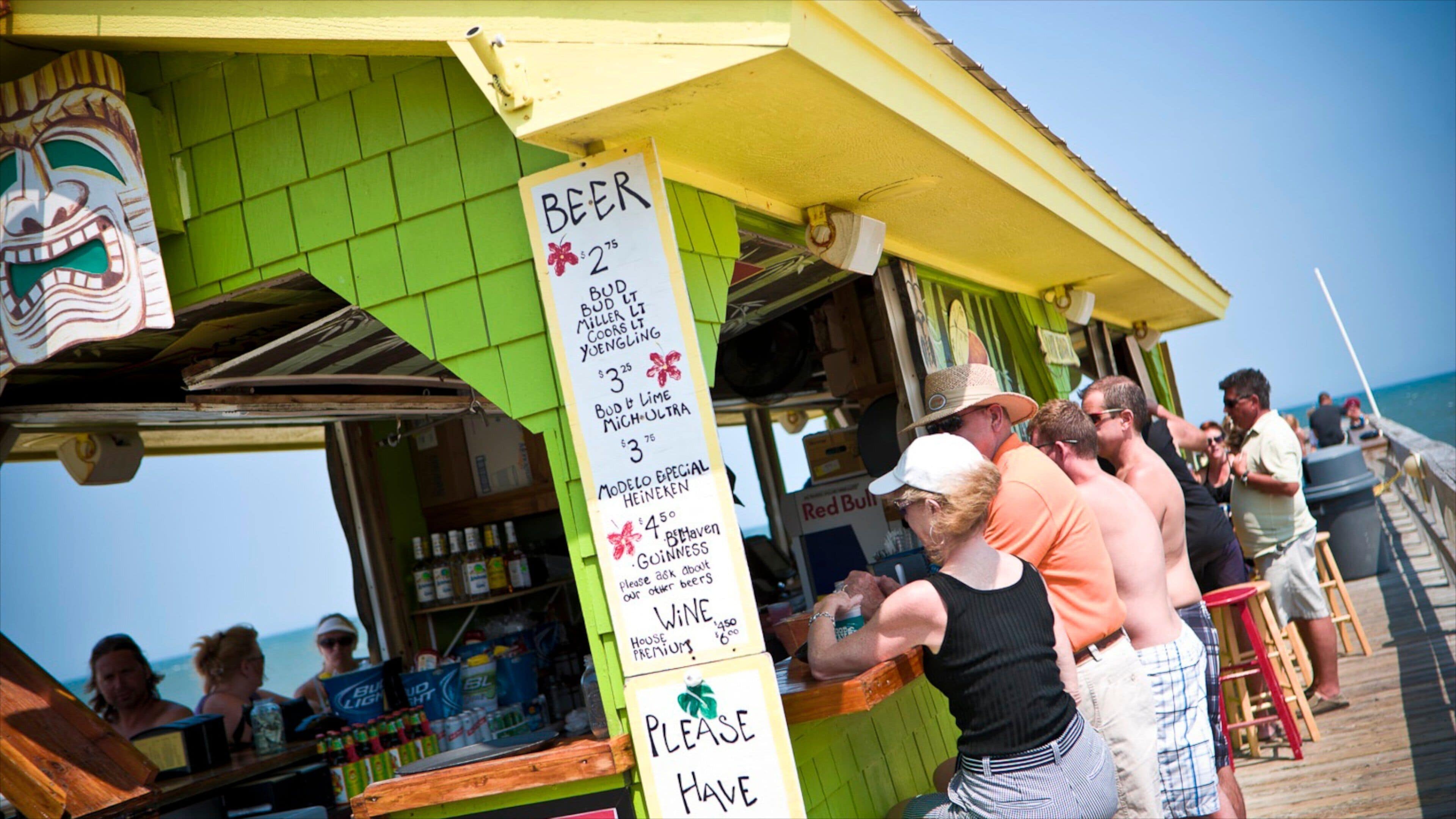Carolina Beach showing a beach bar and signage as well as a large group of people