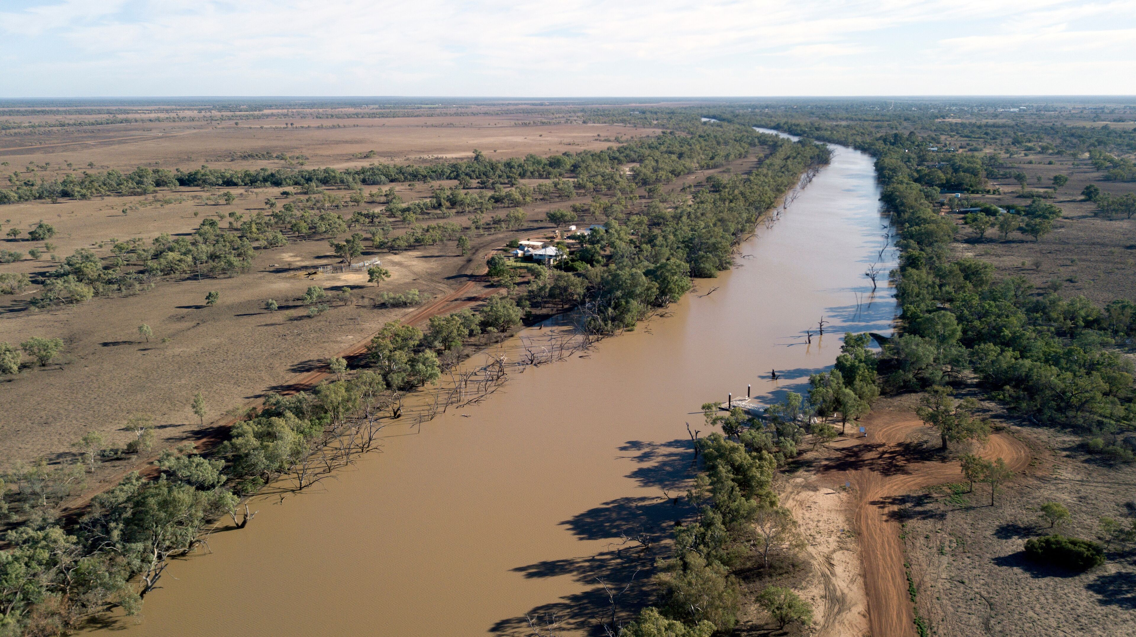 A river winding through a semi-arid landscape with sparse vegetation and a few scattered houses.