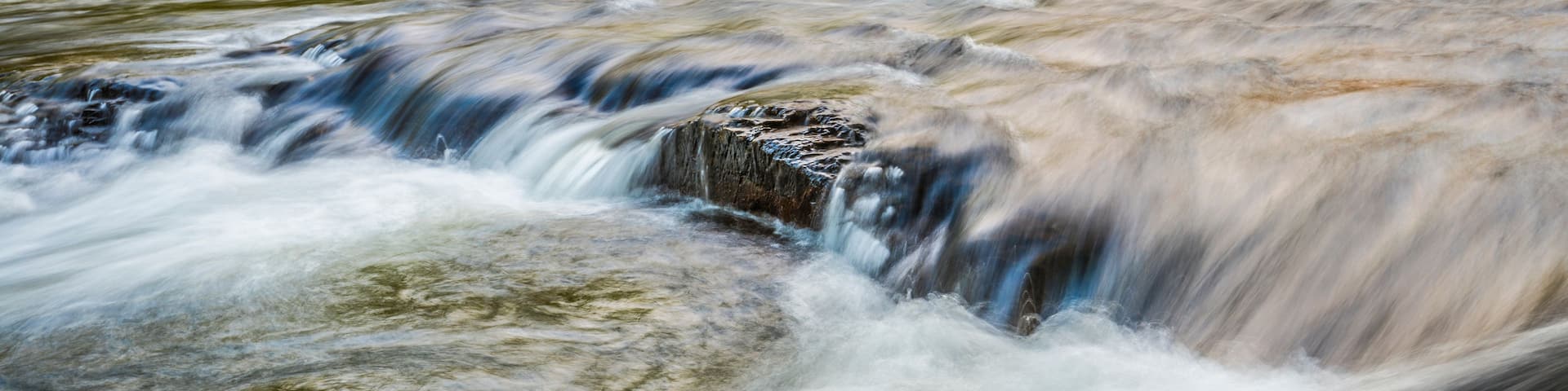 A flowing river with a rocky surface and water cascading over rocks.
