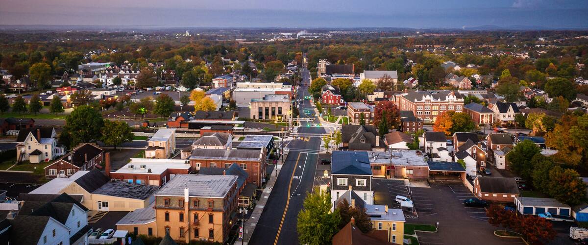 A town with historic buildings, a prominent church steeple, and a wide street.