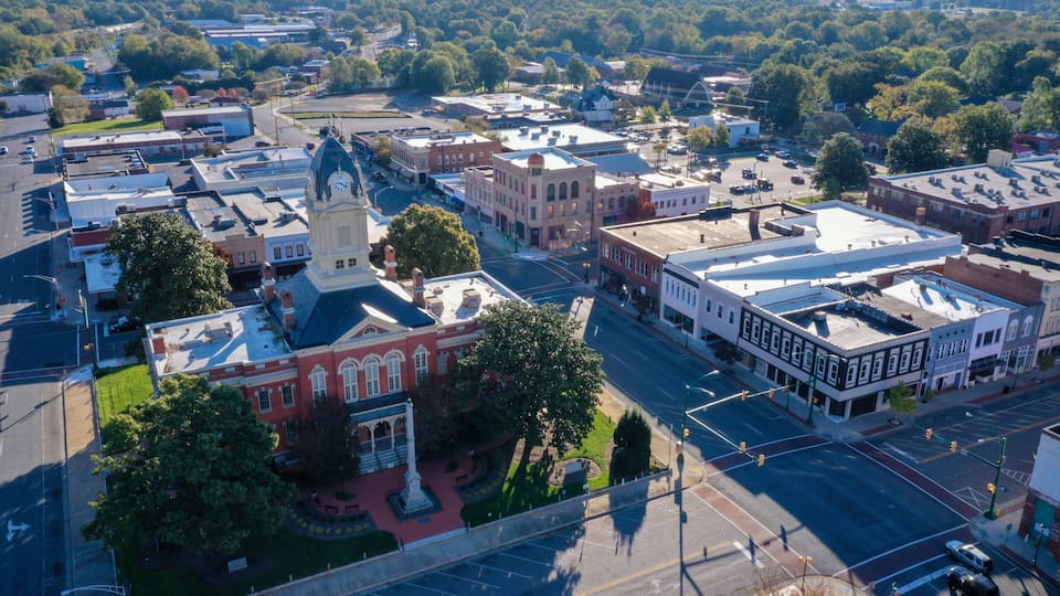 An aerial view of a town with historic buildings, a prominent clock tower, and a central square.