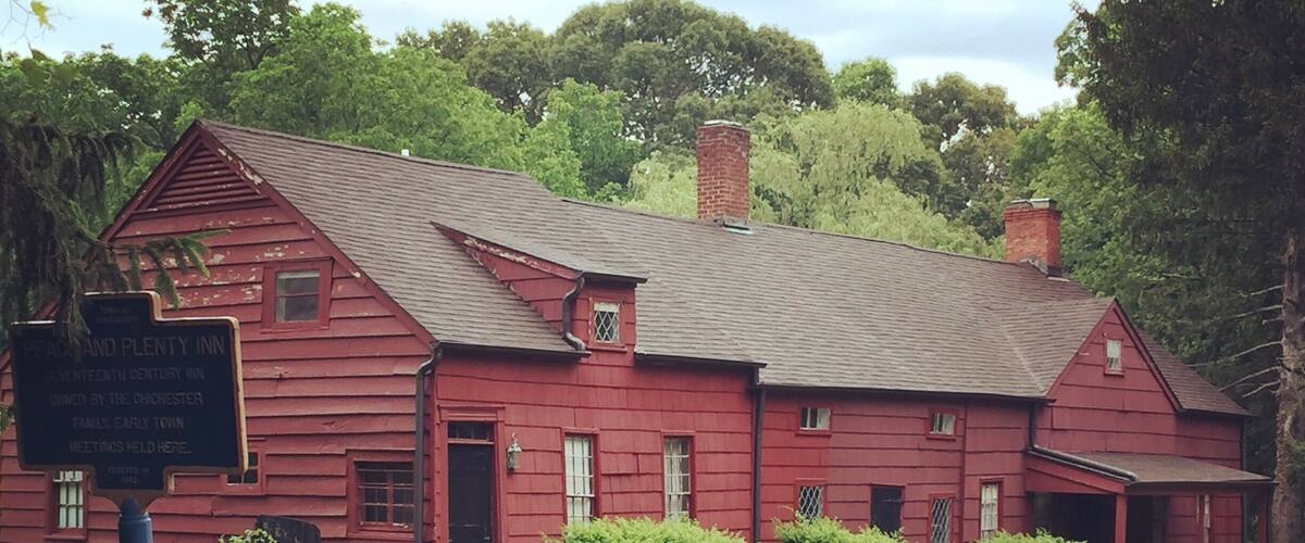 A red wooden building with a sign indicating it is the Peachland and Plenty Inn, a 19th-century inn.