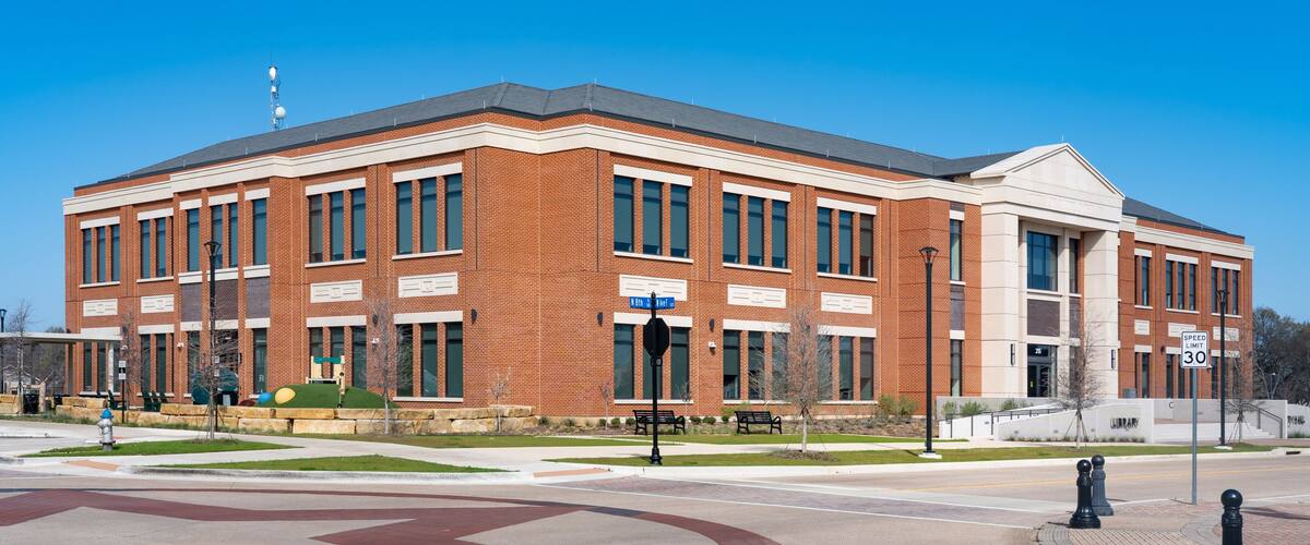 A large brick building with a central entrance, a speed limit sign of 30, and a clear blue sky.