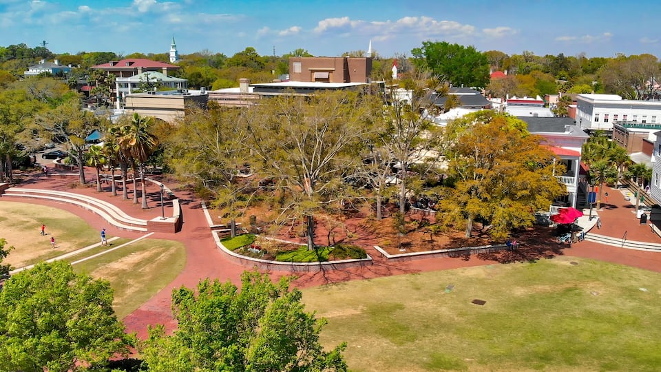 A park with pathways, trees, and buildings in the background.