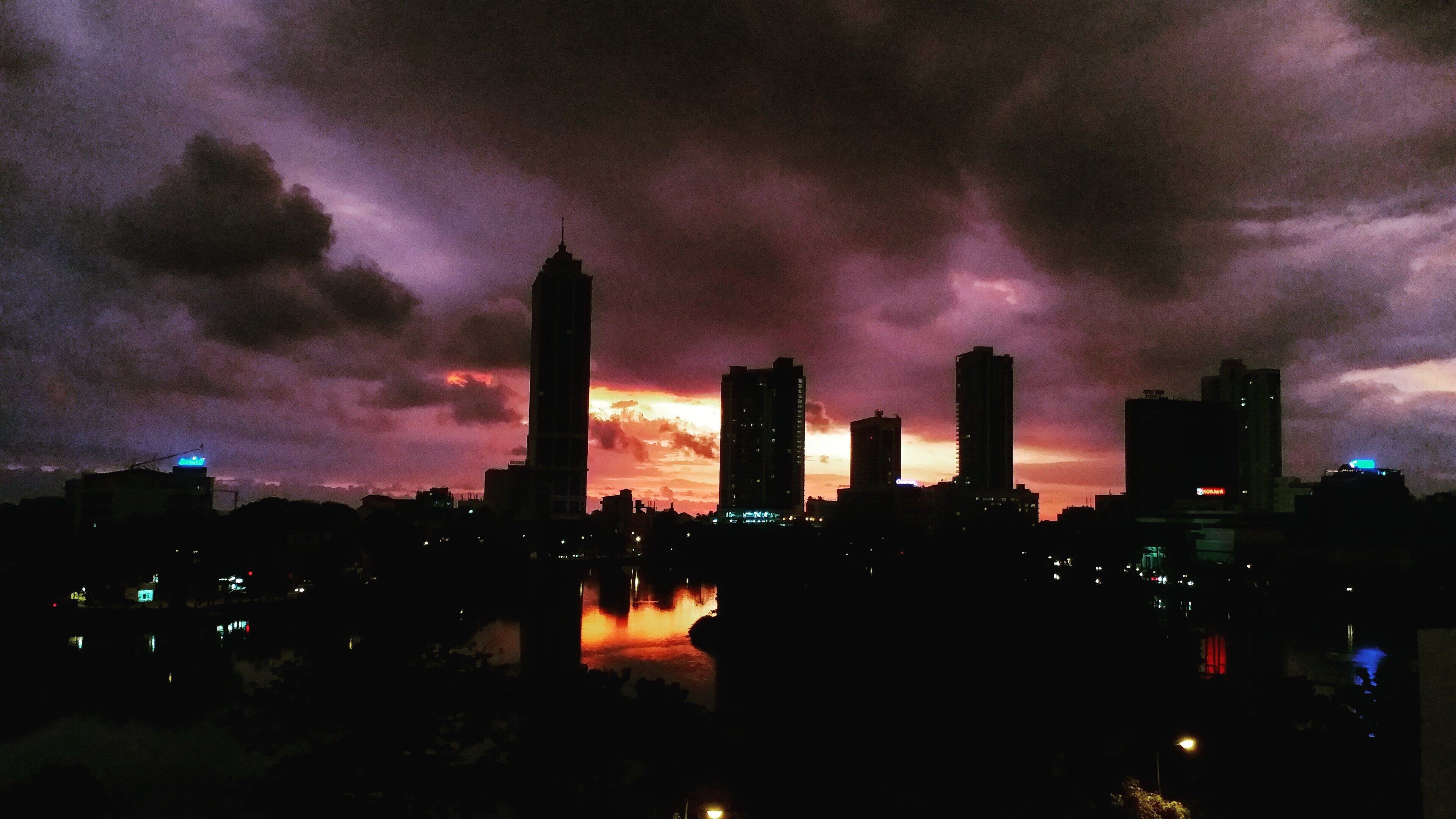 A city skyline at dusk with a dramatic sky.