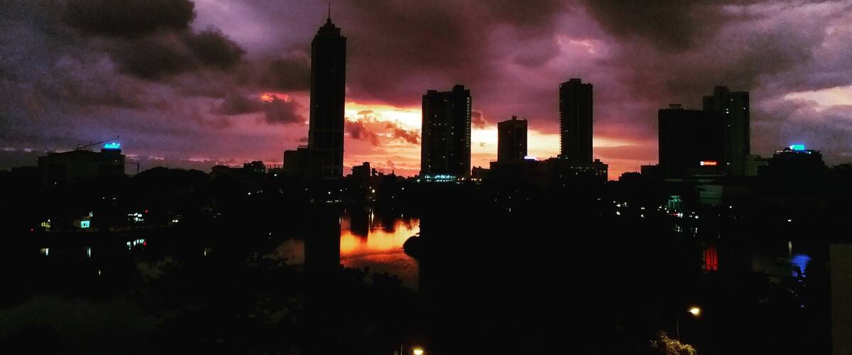 A city skyline at dusk with a dramatic sky.