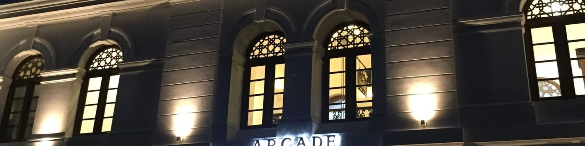 A building with a clock tower and illuminated signage reading "Arcade Square."