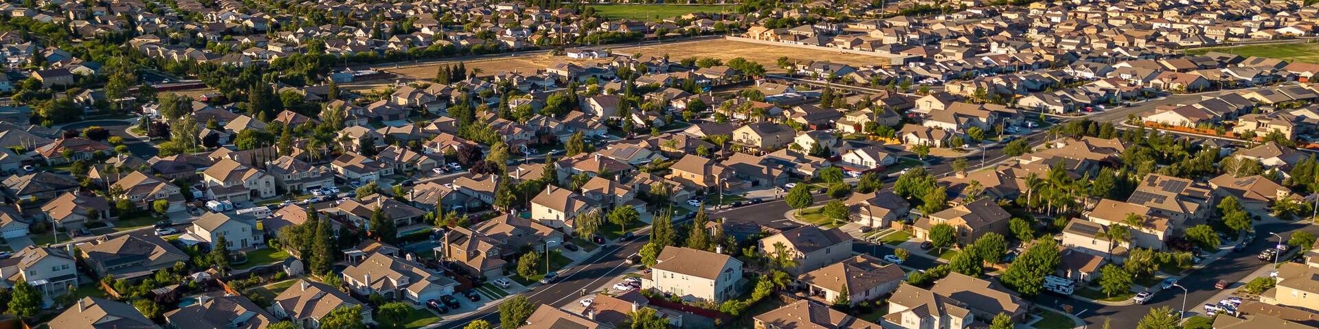 A suburban neighborhood with houses, streets, and a distant industrial area.