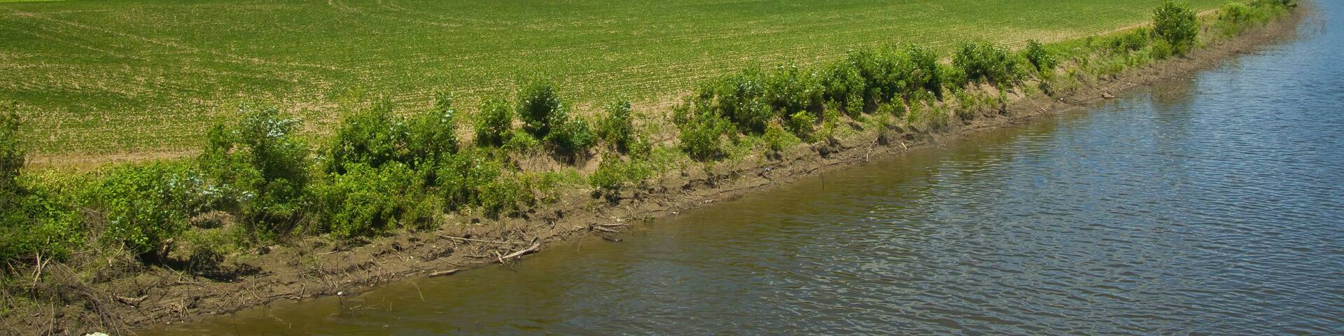 Sunny Summer landscape view of the Missouri River flowing by lush, hilly green farmland along the Katy Trail, near Jefferson City, Missouri.