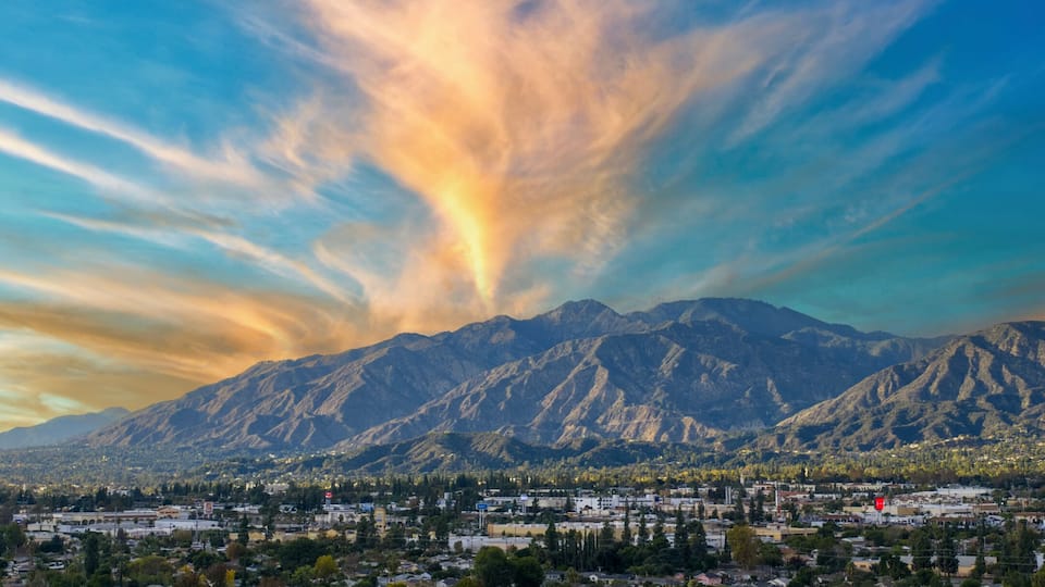 Un paisaje urbano con montañas al fondo y un cielo colorido.