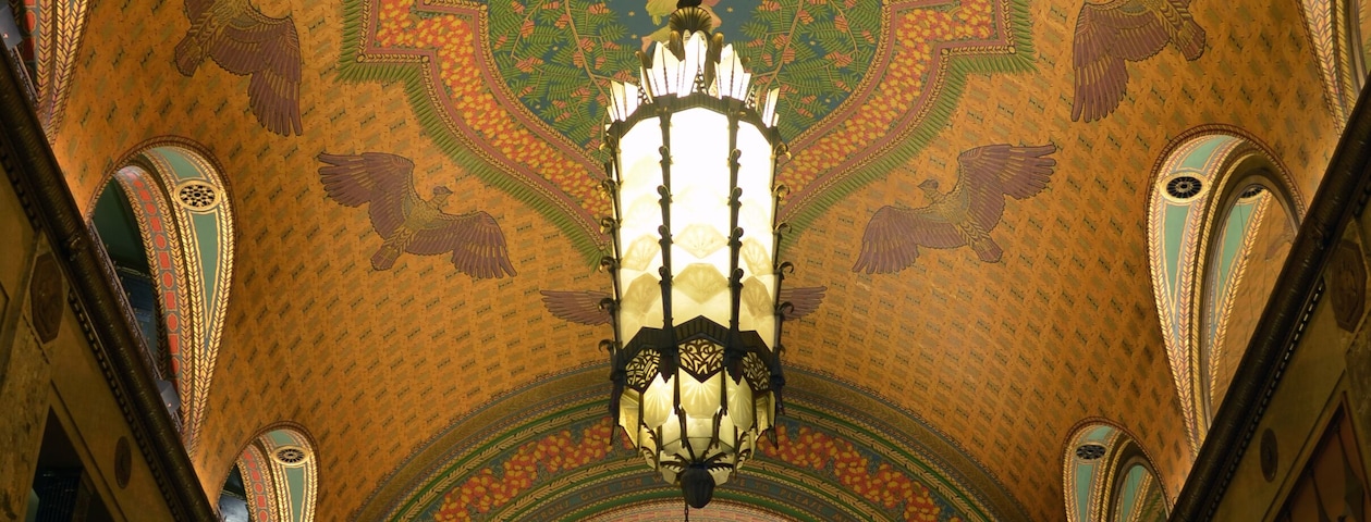 Un intérieur somptueux, orné de fresques au plafond, d’un grand lustre et de fenêtres en arc de cercle.