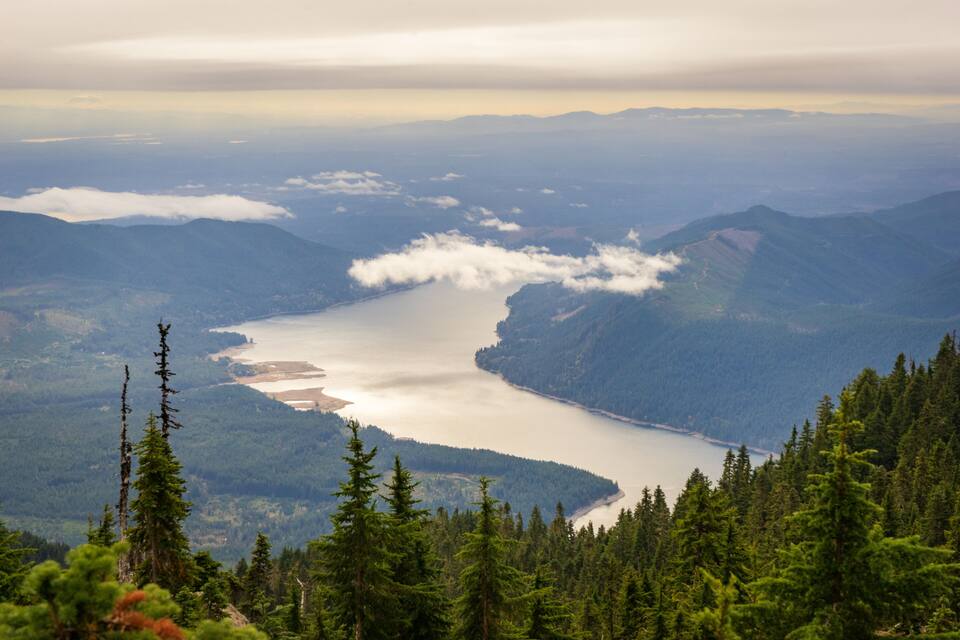 Een meer omgeven door bergen en dichte bossen.