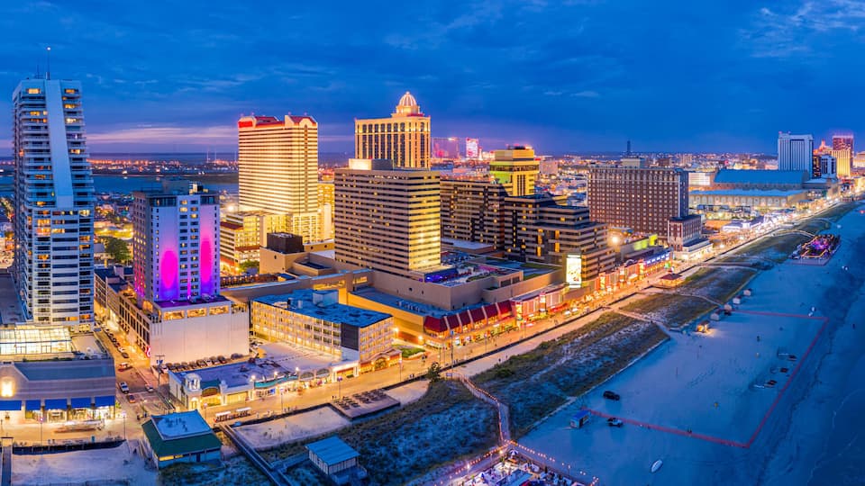 Aerial panorama of Atlantic city along the boardwalk at dusk. In the 1980s, Atlantic City achieved nationwide attention as a gambling resort and currently has nine large casinos.