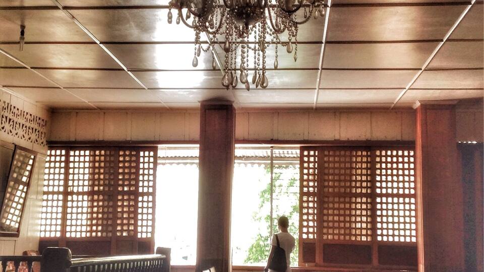A traditional interior with a chandelier, wooden columns, and a table with a lace tablecloth.