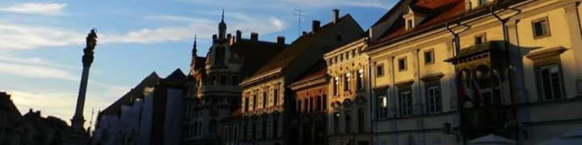 A historic town square with a prominent clock tower, traditional buildings, and a clear blue sky.