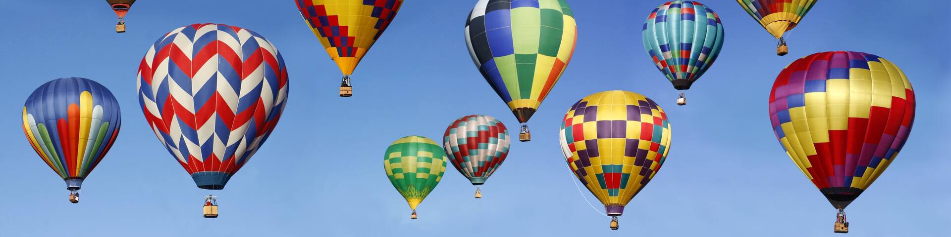 A variety of colorful hot air balloons against a clear blue sky.