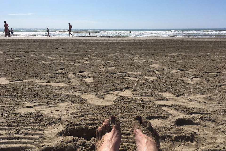 A beach with footprints and people in the distance.
