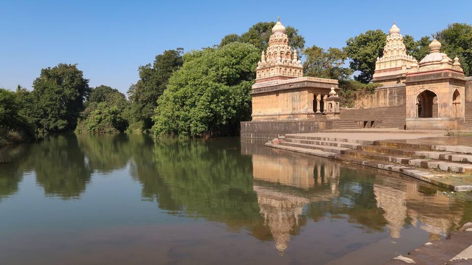 A temple with intricate architecture by a calm river, surrounded by lush greenery.