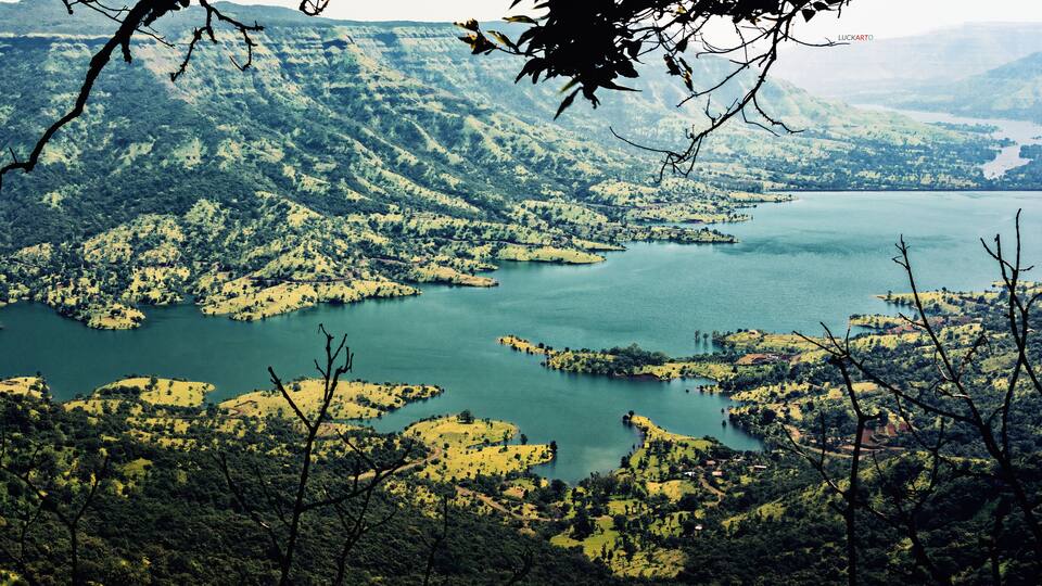 A mountainous landscape with a large lake surrounded by forested areas and scattered settlements.