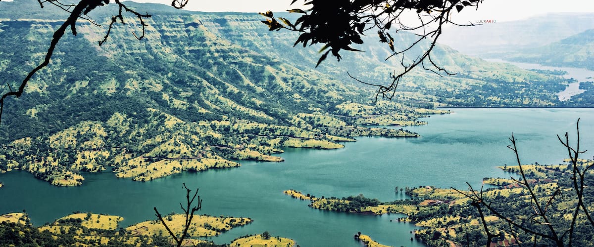 A mountainous landscape with a large lake surrounded by forested areas and scattered settlements.