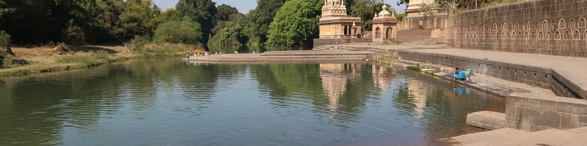 A calm river with a temple and steps leading to it.