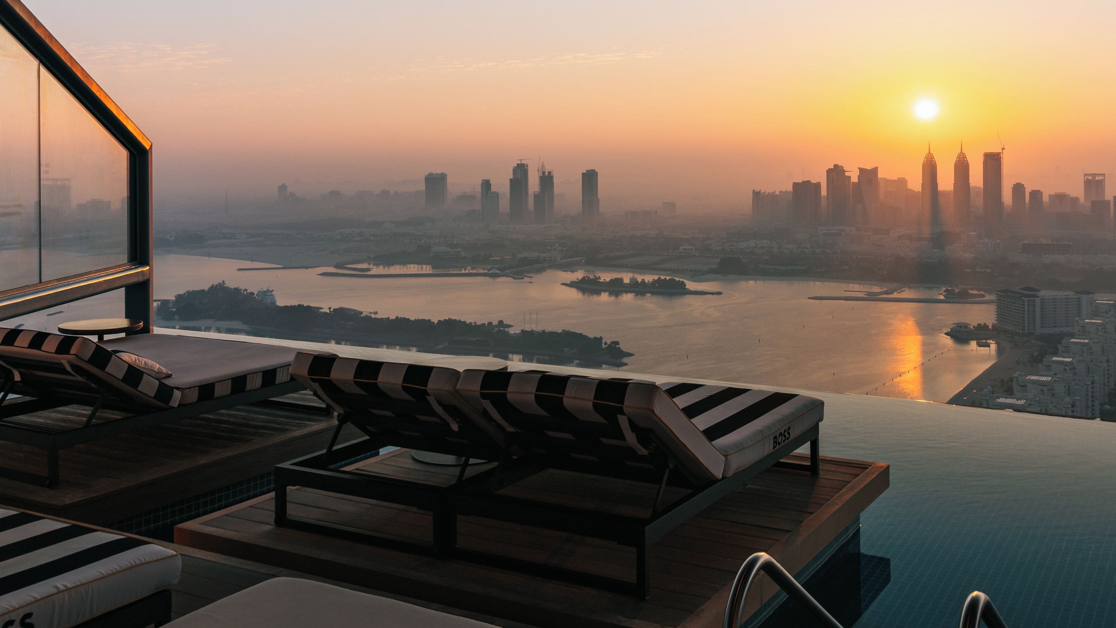Vista al atardecer desde un balcón alto con vistas a un horizonte urbano y un río.