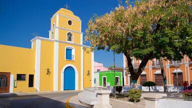 A yellow church with a blue door and a bell tower.