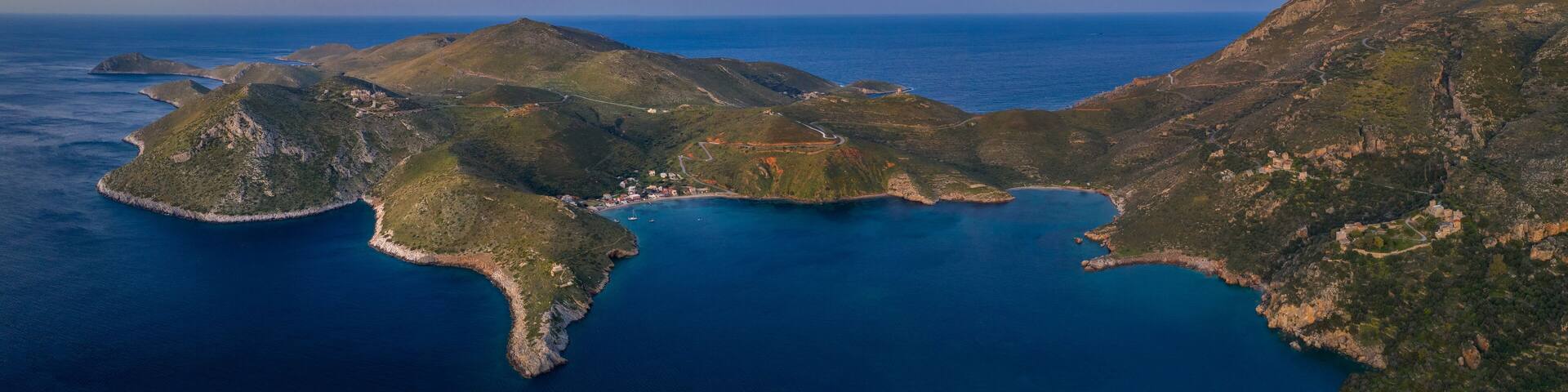 An aerial view of a rugged coastline with multiple islands, clear blue waters, and a mix of rocky terrain and greenery.