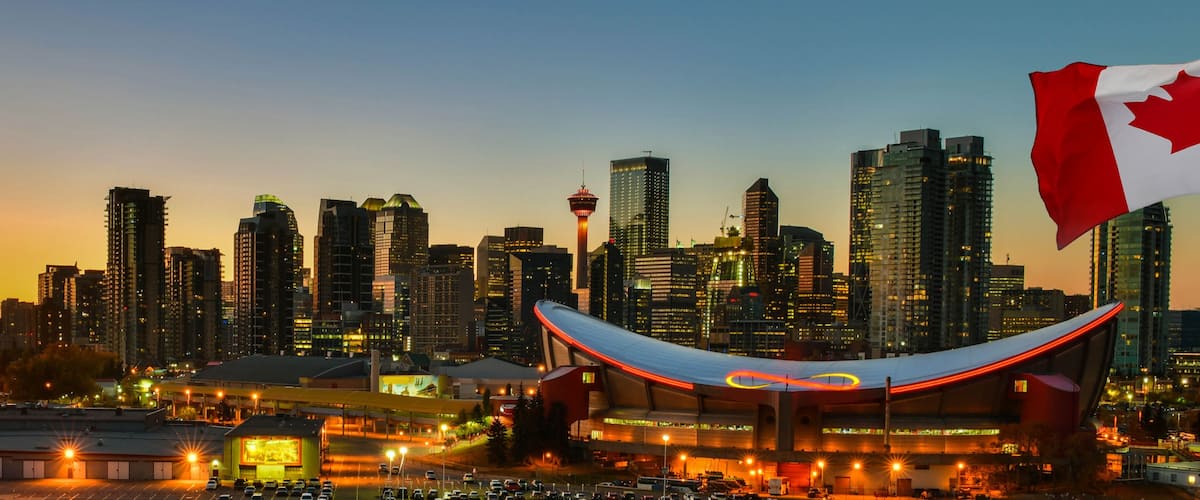 A city skyline at dusk with a prominent stadium and a flag.