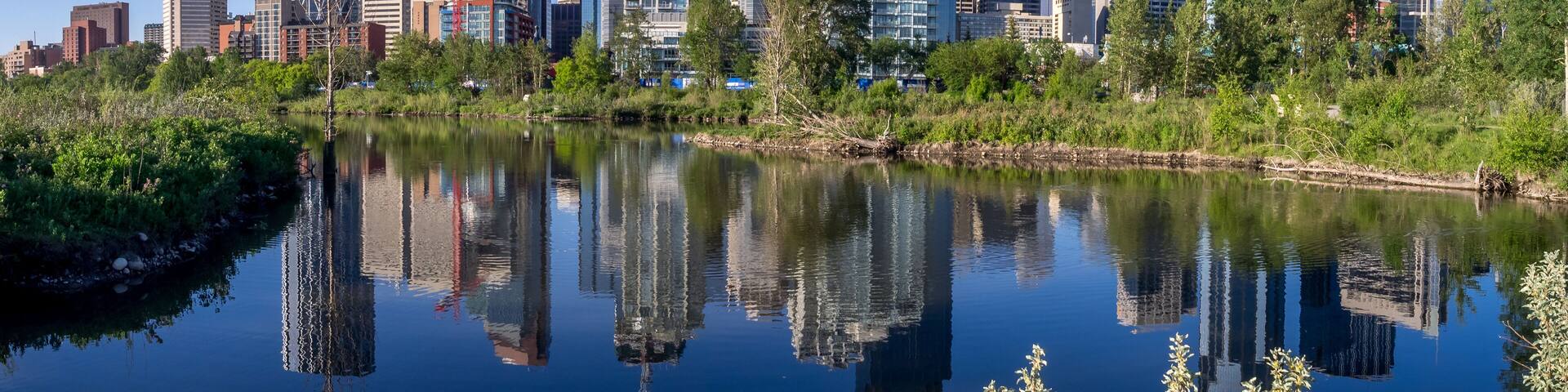 A city skyline with modern skyscrapers and a calm river reflecting the buildings.