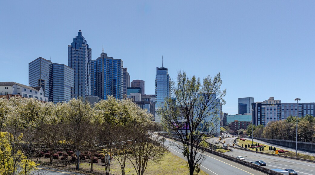Downtown Atlanta Skyline showing several prominent buildings, highways, cars and hotels under a blue sky.