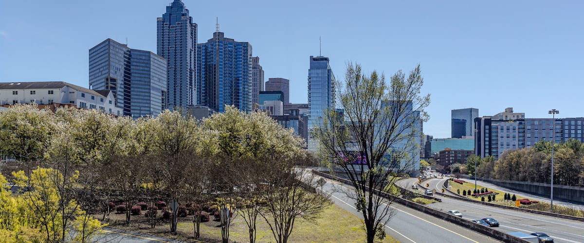 Downtown Atlanta Skyline showing several prominent buildings, highways, cars and hotels under a blue sky.