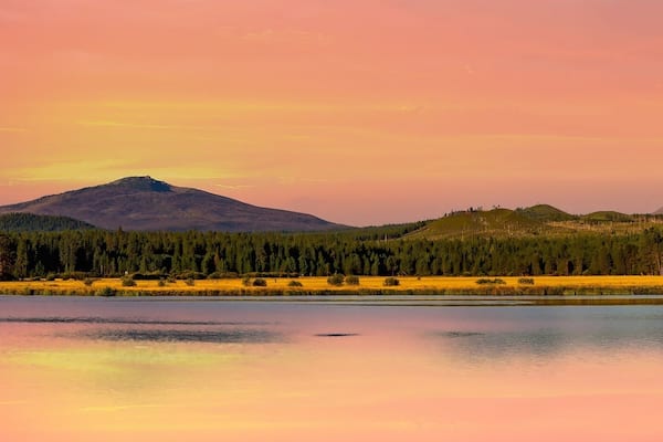 The three sisters and Mt washington mountains and lake Phalarope at sunmset at Black Butte Ranch in a panorarama imasge near Sisters, Oregon