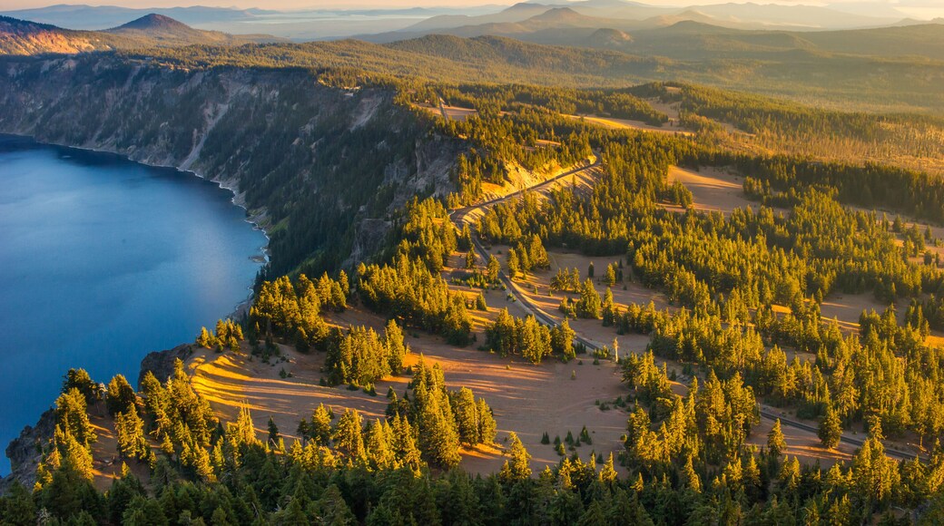 A mountainous landscape with a forested area, a clear blue lake, and a winding road.