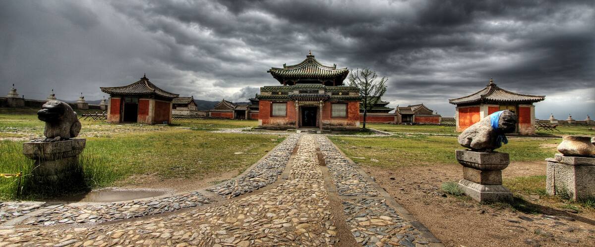 A traditional Chinese temple complex with a central building and two smaller structures on either side, surrounded by a stone pathway and stone lion statues.
