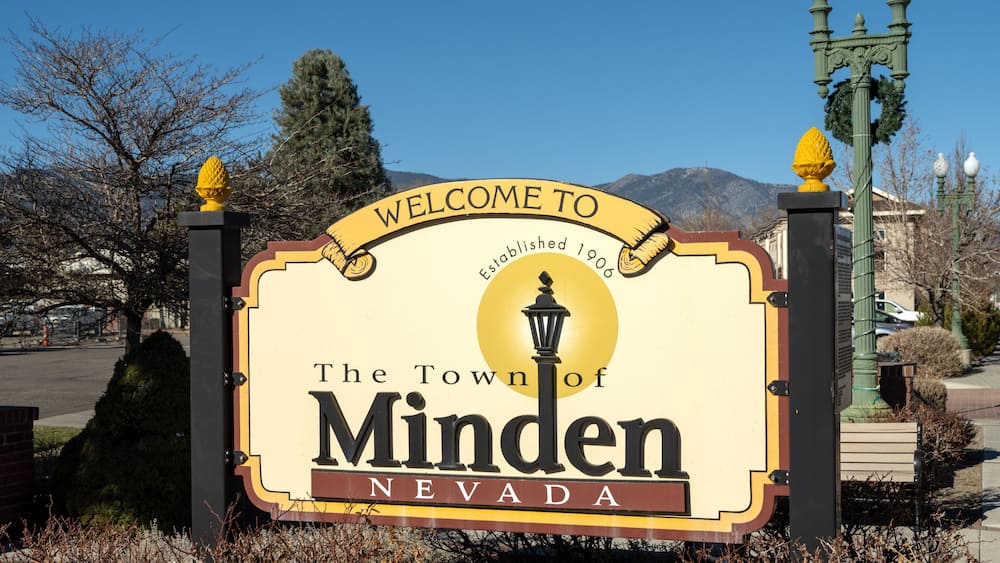 A welcome sign for The Town of Minden, Nevada, with a mountain backdrop.
