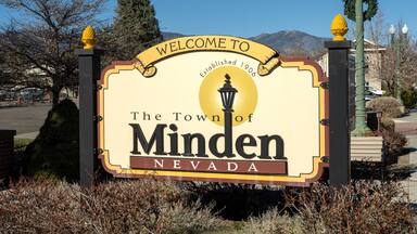 Un cartel de bienvenida al pueblo de Minden, Nevada, con montañas al fondo.