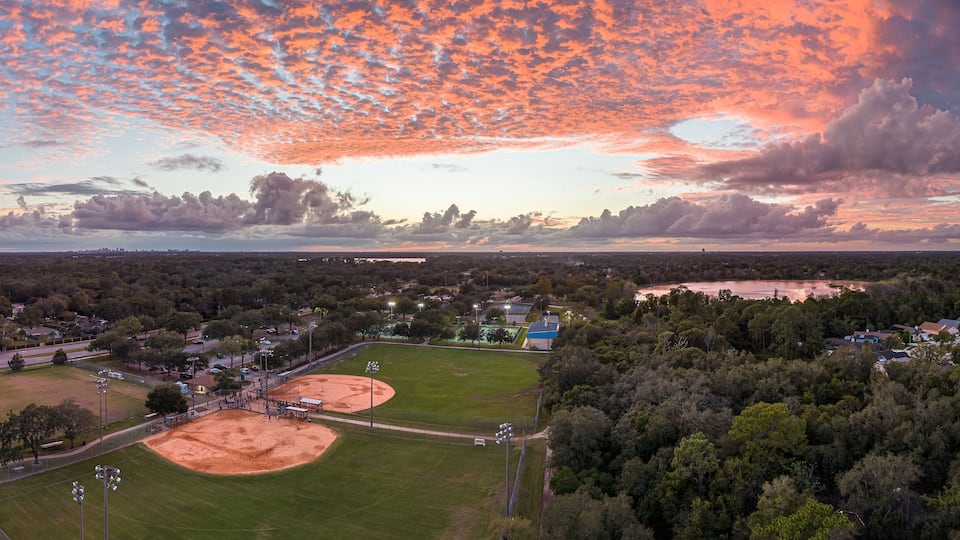 A baseball field surrounded by trees and a lake.